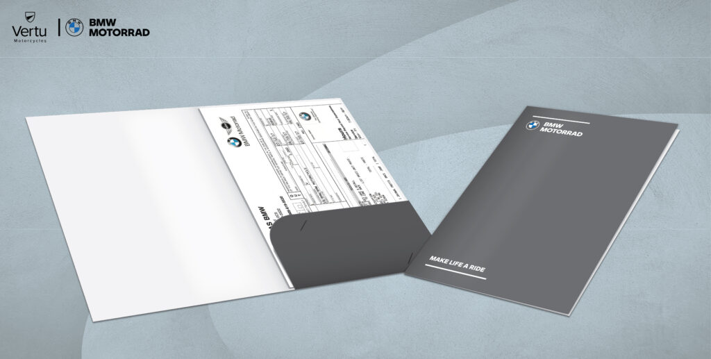 Grey BMW Motorrad dealer handover folder for Vertu Motorcycles, shown open with paperwork in the pocket