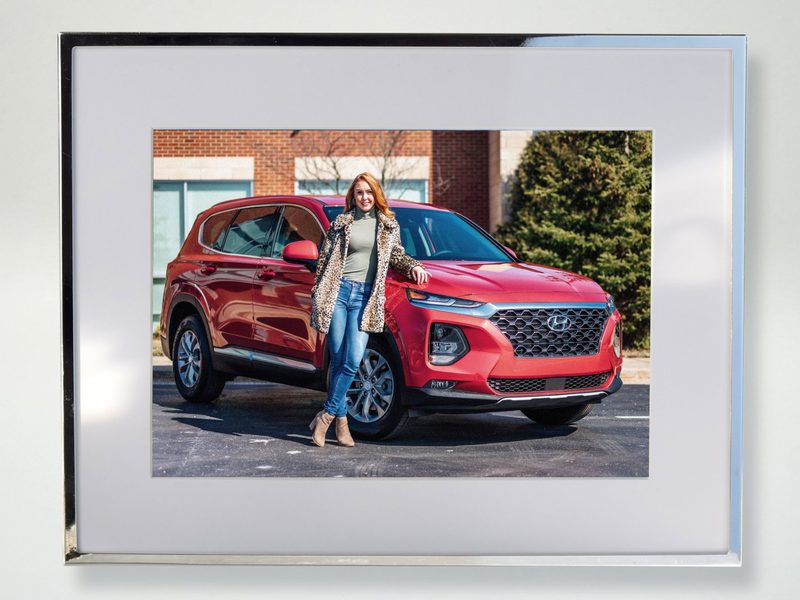 Silver photo frame with brand plaque showing a customer with their new car